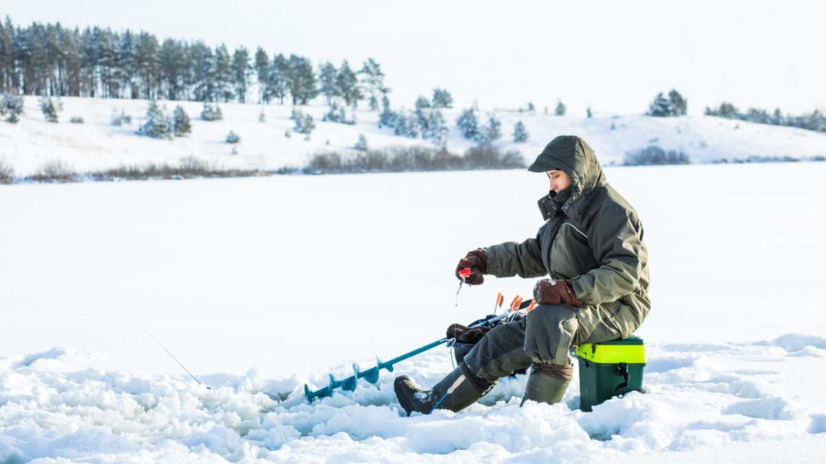 A young man is fishing from a hole on ice. Winter fishing.