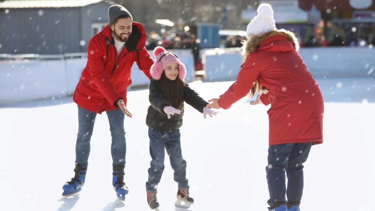 Happy family spending time together at outdoor ice skating rink