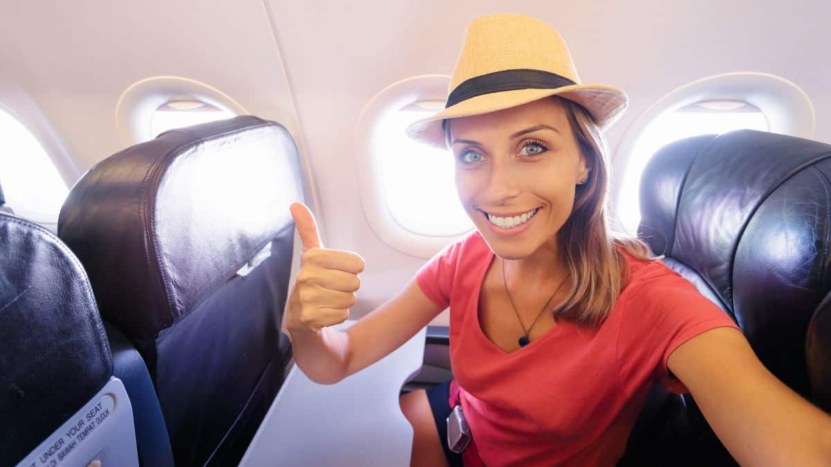 woman on airplane giving thumbs up using scotts cheap flights