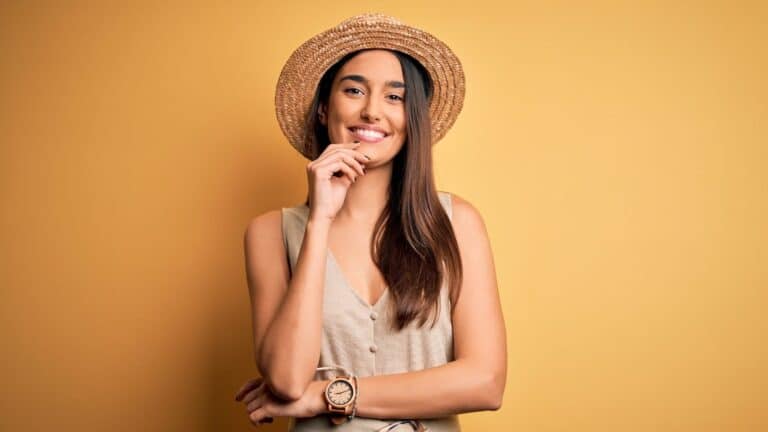 Young beautiful brunette woman on vacation smiling with crossed arms and hand raised on chin