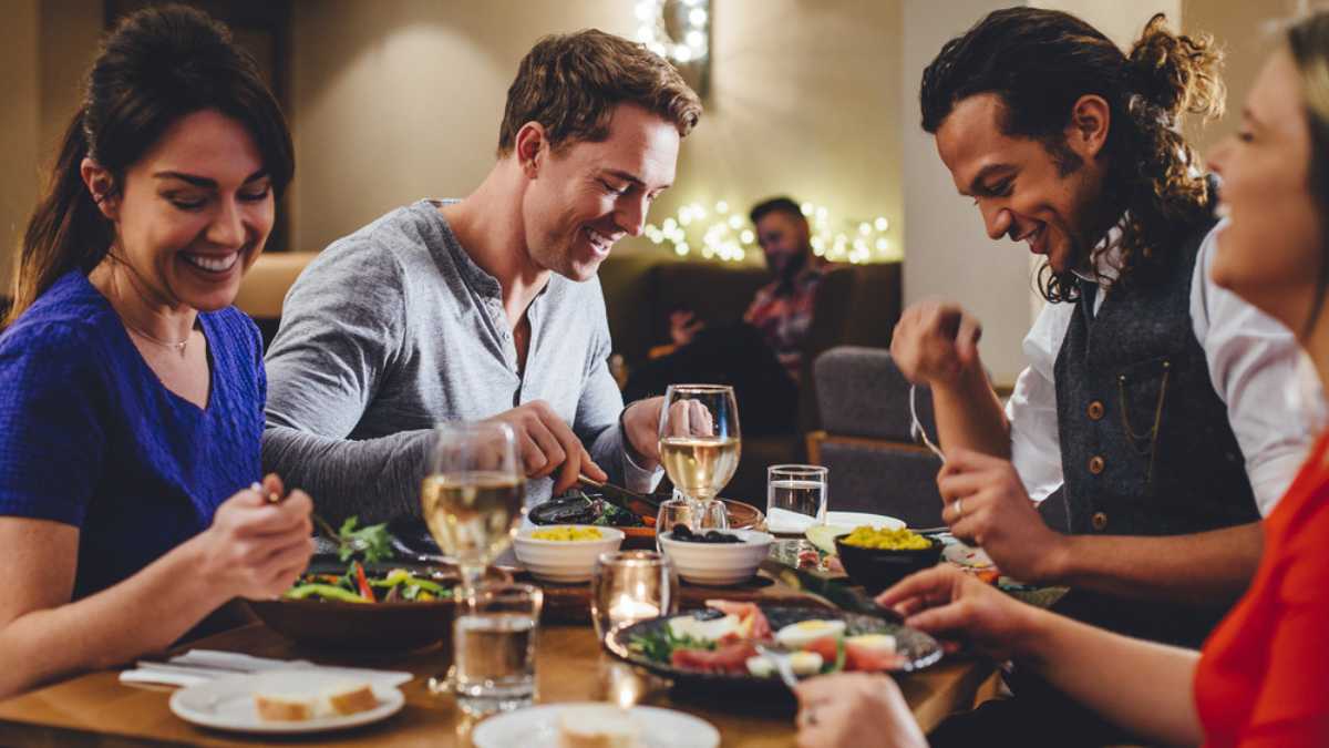 Group of friends enjoying an evening meal with wine at a restaurant.