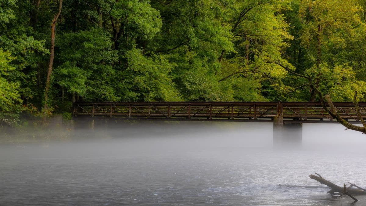 A foot bridge crosses over the South Holston River and the low fog that hangs over the water.