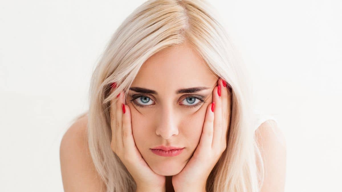 Blonde face is laying on her hands. The concept of frustration,fatigue, sadness. studio photo on white background