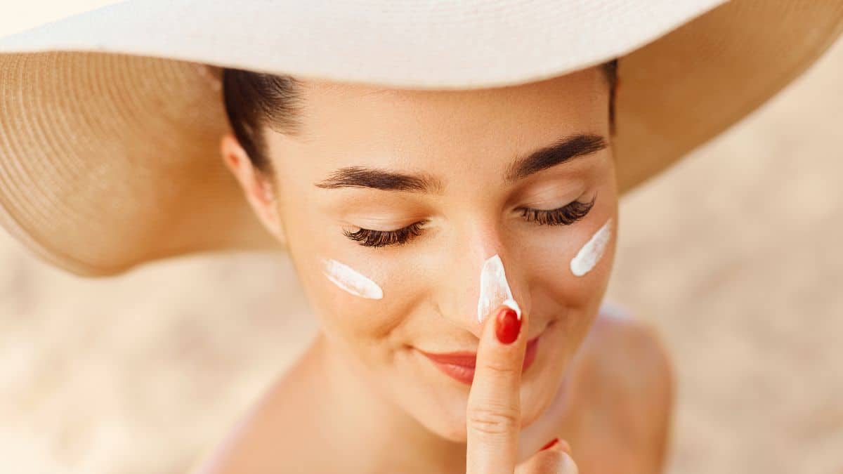 Beautiful Young woman with sun cream on face.