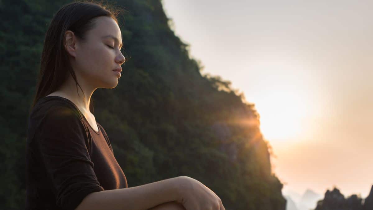 woman relaxing and meditating in nature, during sunset. Peaceful zen.