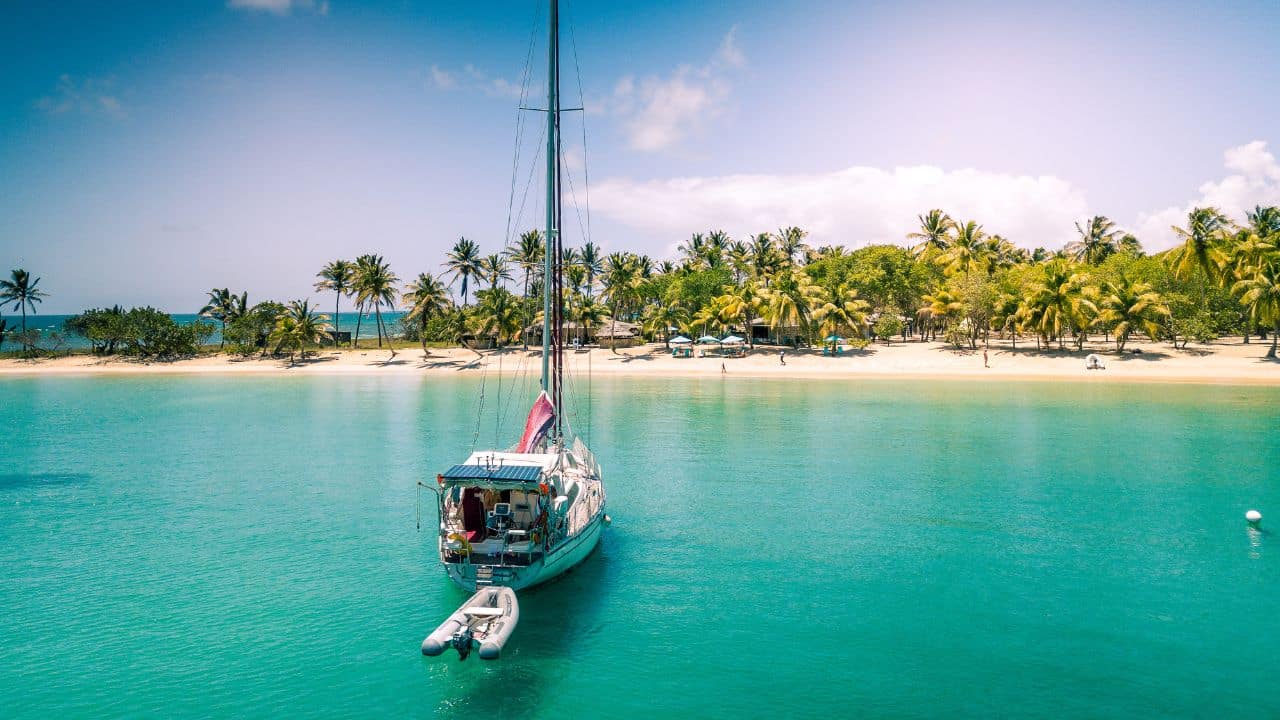 isolated sailboat anchoring on Mayreau - St-Vincent and the Grenadines - Caribbean island. Palm trees on white sand beach