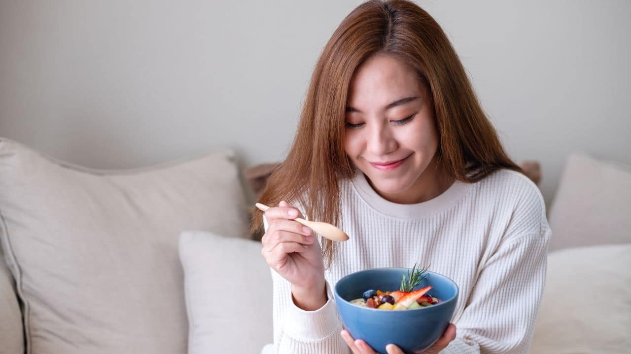 A young asian woman eating healthy blueberry smoothie bowl