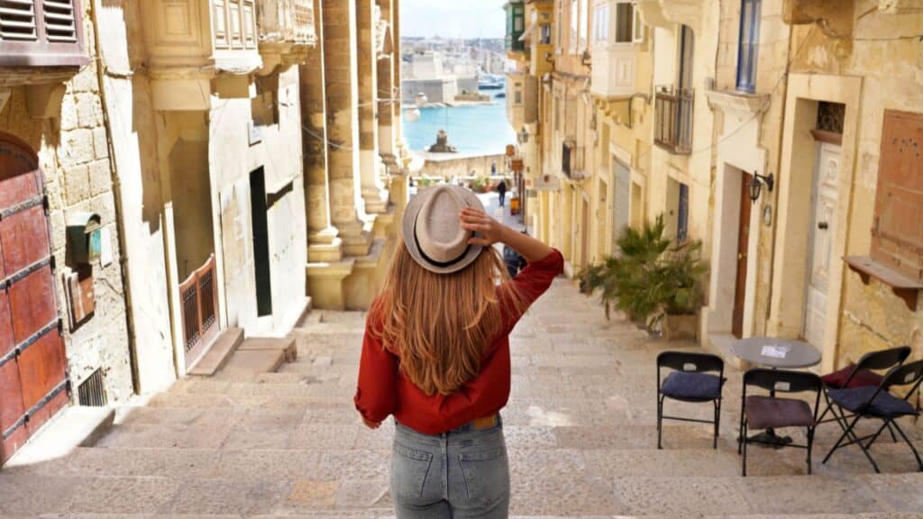 Holidays in Malta. Back view of traveler woman descends stairs in the historic city of Valletta, UNESCO World Heritage, Malta.