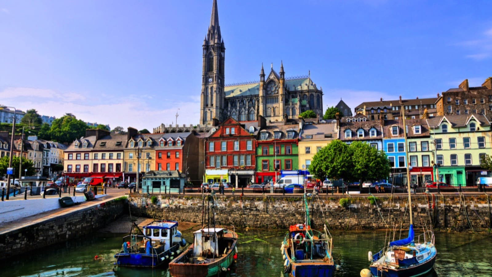 Colorful buildings and old boats with cathedral in background in the harbor of Cobh, County Cork, Ireland